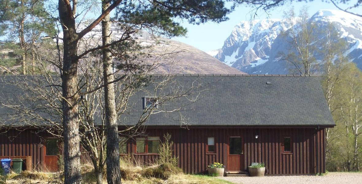 Great Glen Holidays Header wooden chalet with Ben Nevis in the background