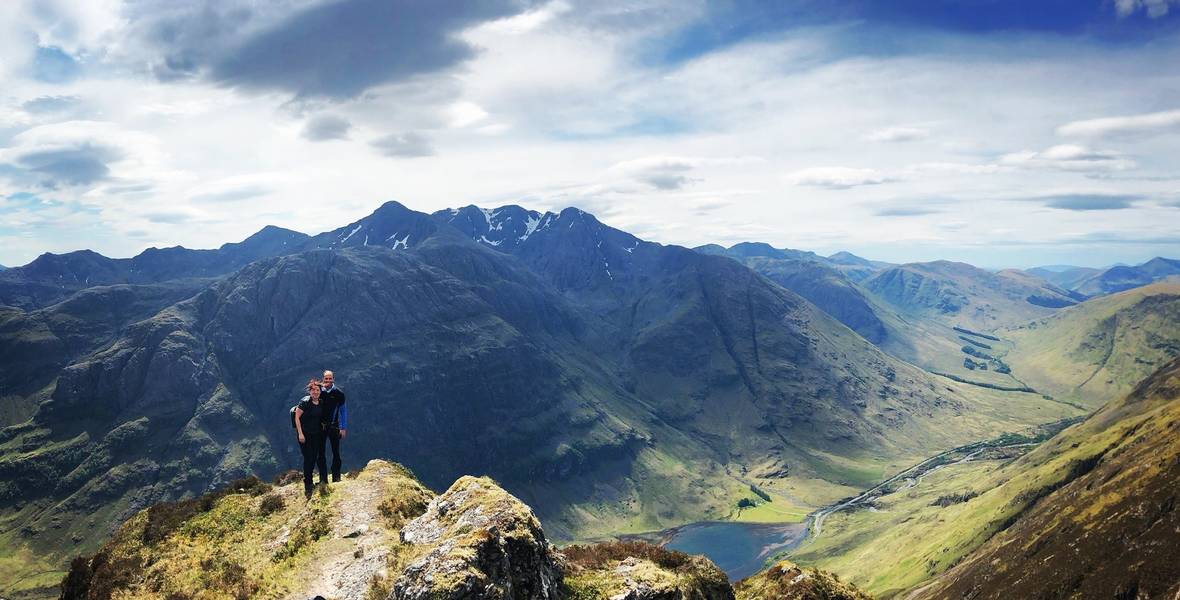 Hunter Mountaineering Header Couple standing on top of a ledge looking over a mountain range
