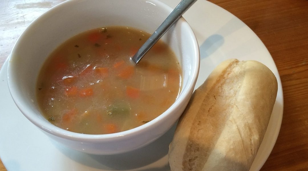 bowl of Scotch broth and a bread roll on the side of the plate