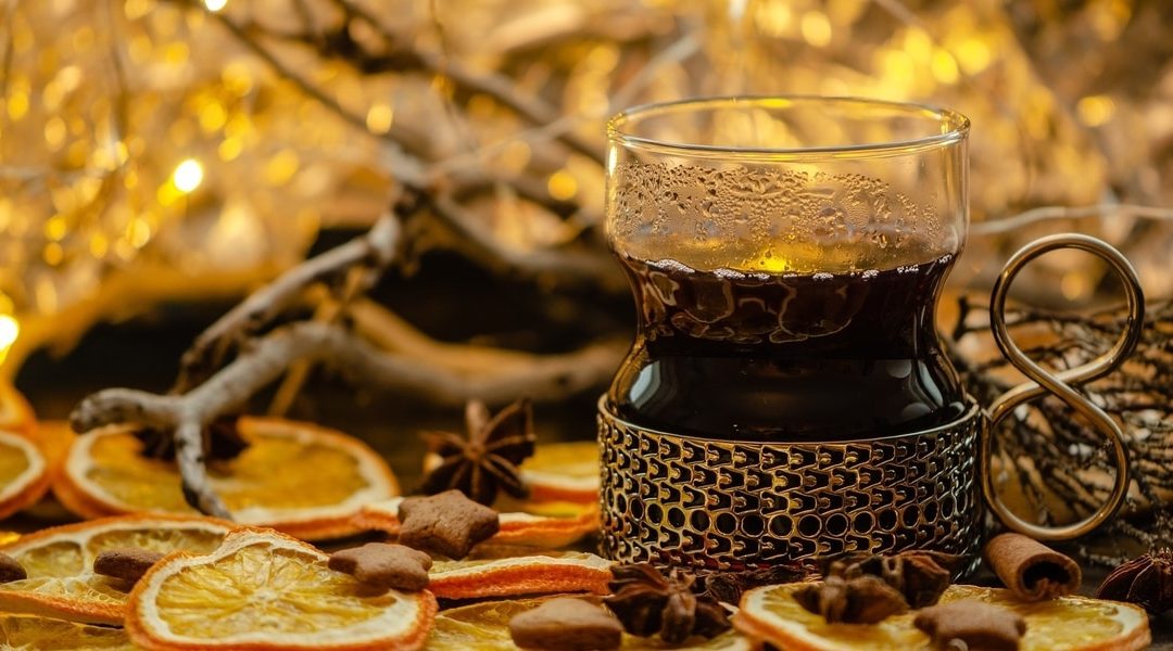 Hot toddy in decorative glass surrounded by dried oranges and cinnamon stars